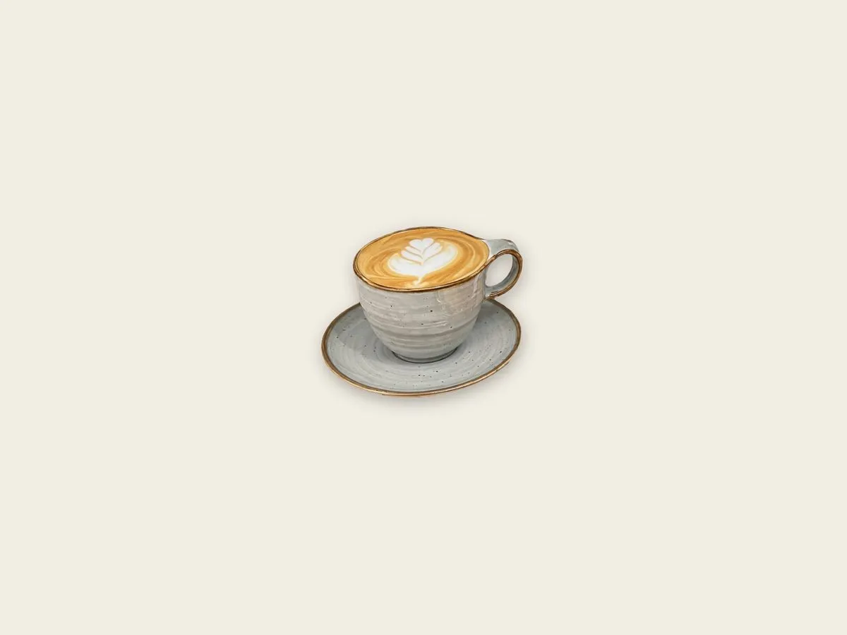Capuchino con arte en leche servido en taza de cerámica
