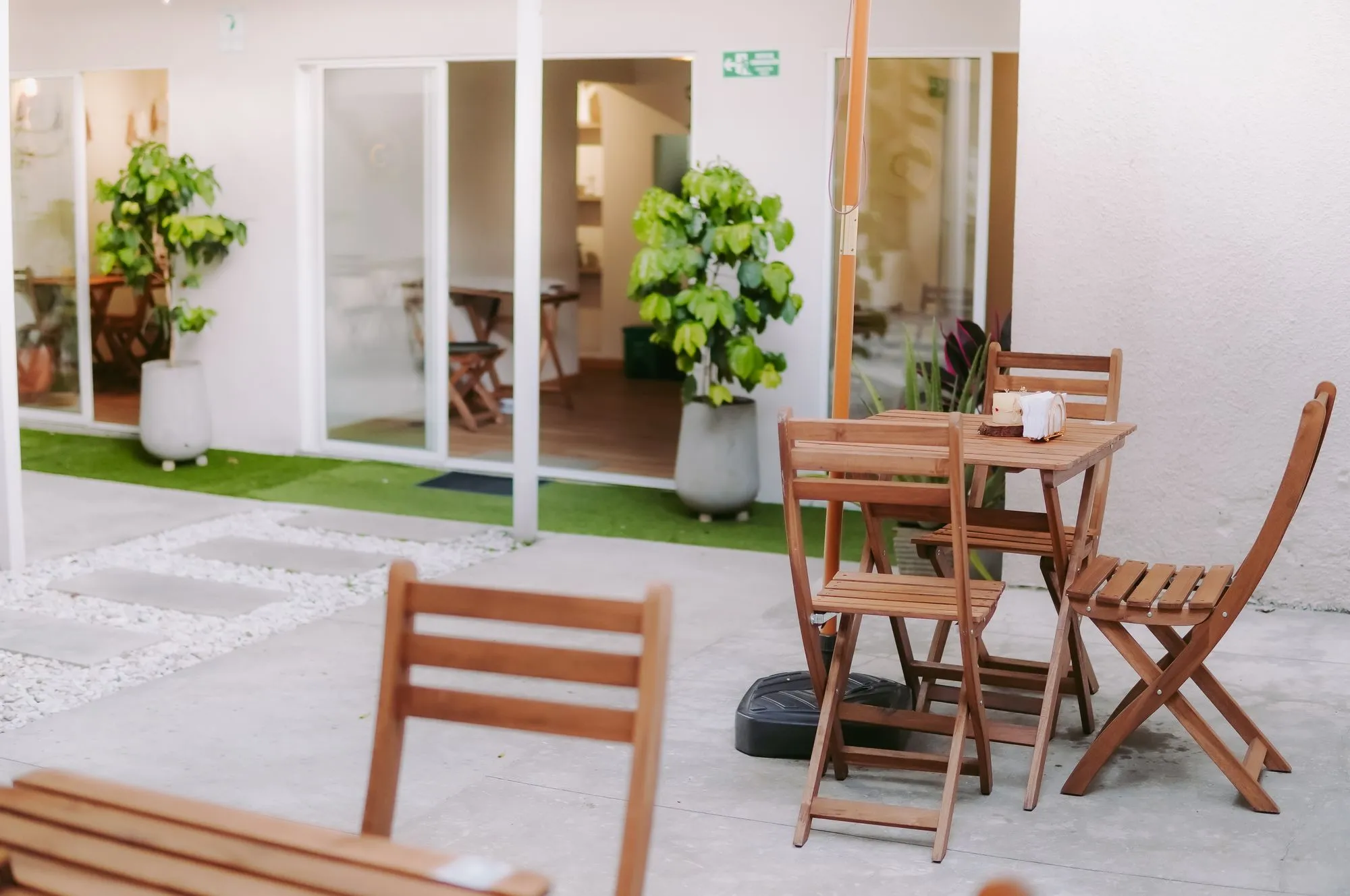Mesas de madera en el patio de CAELUS, con el paso hacia el salón al fondo